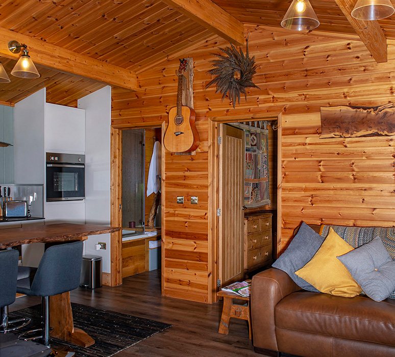 Colby cabin luxurious & modern wooden interior a leather sofa, well fitted modern kitchen and bathrooms can be seen through open inerior doors